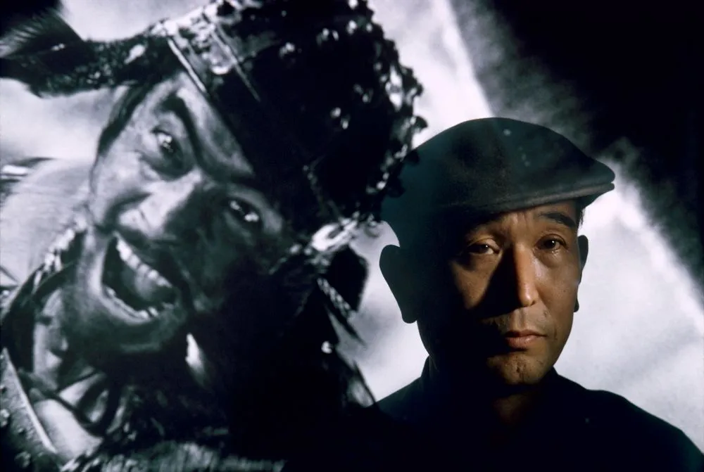Film director Akira Kurosawa standing before an image of his principal star, Toshiro Mifune, Tokyo. From a series on the Asian film industry for ‘Life’