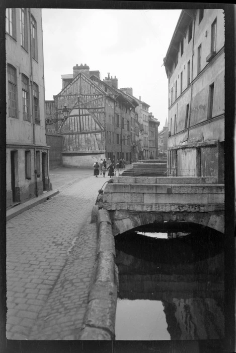 An cobblestone backstreet with people and four storey houses beside a ...