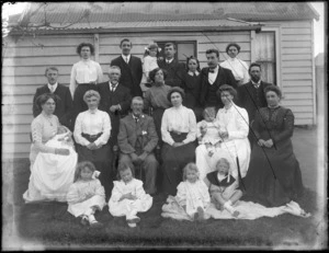 Group of unidentified men and women and children, with a single-storied wooden house behind, probably Christchurch district