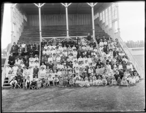 Large crowd of unidentified people sitting in a grandstand, [at a racecourse?], probably Christchurch district