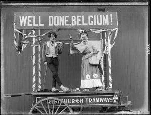 Two unidentified clown entertainers on a Christchurch Tramways wagon, which is decorated with ribbons and a sign reading 'Well done, Belgium!', probably Christchurch district