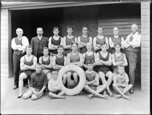 Group of unidentified men and boys in swimming costumes [swimming team? lifeguards?], with a lifesaving ring buoy stamped with the letters 'WBC', possibly Christchurch district