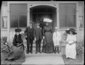 Family group, showing three women, two men, and a boy, all unidentified, standing on the front steps of a wooden house, possibly Christchurch district