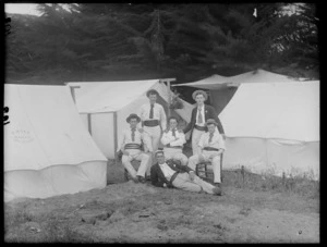 Group of six unidentified men, wearing cummerbunds, at a campsite, Christchurch district