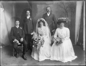 A wedding portrait of an unidentified bride and groom with the wedding party, taken in the studio, possibly Christchurch district