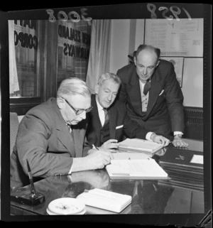 Sir Len Isitt with two other men signing a contract for Tasman Empire Airways Limited