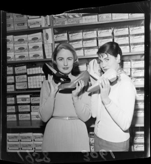 Two unidentified shop assistants showing the lastest shoe fashions in at Martin's Shoe Store, Wellington