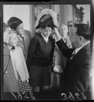 A party of children from Otago visiting the Mayor of Wellington, Frank Kitts, with one of them wearing his ceremonial hat
