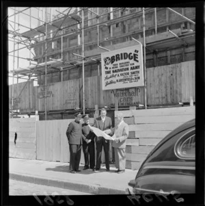 Mayor Frank Kitts looking at plan drawings with Salvation Army officers, outside 'The Bridge', a building under construction for The Salvation Army