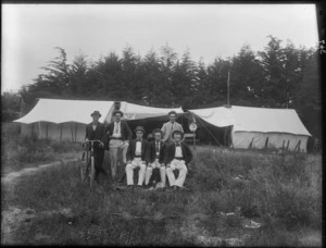 Group of unidentified young men wearing straw boaters, one man with a bicycle, sign on tents behind reads 'Red Rose Camp', [New Brighton, Christchurch district?]