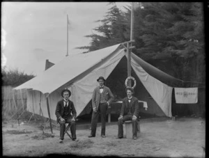 Group of unidentified men at a campsite, includes life saving buoy hanging on tent and sign reading 'Red Rose' [New Brighton, Christchurch?]