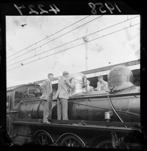 Unidentified men polishing a vapour dome on a steam train, on the occaision of the 50th anniversary of the Manawatu Railway