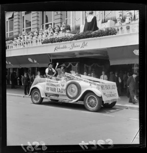 Julie Andrews and Rex Harrison impersonators in car promoting 'My Fair Lady' record (Coronet label), with Kirkcaldie and Stains Ltd department store (with Christmas decoration including choir and organ) in the background