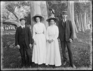 Two unidentified couples wearing hats under trees, probably Christchurch district