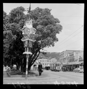 Father Christmas decoration on pole, Courtenay Place, Wellington, including pohutukawa trees and tram