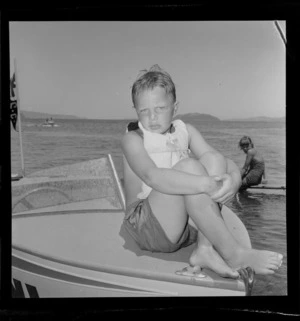 Young unidentified boy sitting on a speed boat, water skiing at Petone, Lower Hutt