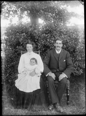 Family group, showing unidentified man, woman, and young child, in a garden, possibly Christchurch