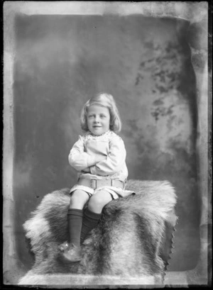 Studio portrait of an unidentified young child, wearing a tunic with a lace collar, possibly Christchurch district