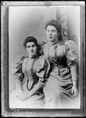 Studio portrait of two unidentified women, wearing similar dresses, probably Chrischurch district - Photograph taken by Mercers, [of Enniskillen, Northern Ireland?]