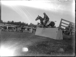 Autumn Show, man with pinto horse jumping a wooden fence, with spectators beyond, Hawke's Bay District