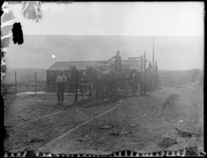 View of two men with a horse drawn wagon carrying milk pails, large barn behind, Hawke's Bay District