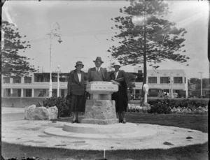 Unidentified man and women standing at the Kirk Sundial, Marine Parade, Napier