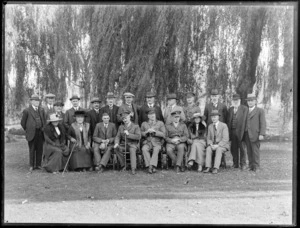 Unidentified group of men and women, some in uniform, posing in front of a river, [Christchurch?]