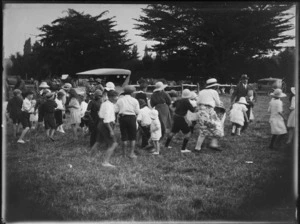 Children having a lolly scramble in a field, Hawke's Bay District