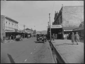 View of the main street of a town [Hastings?], with people shopping and commercial businesses, 'Thos Ritchie Ltd Plumbers & Electricians', 'Becks Pharmacy', Hawke's Bay District