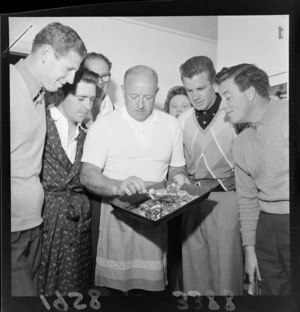 Unidentified golfers looking at tray of food held by a cook, Paraparaumu Golf Club, Kapiti Coast District, Wellington Region