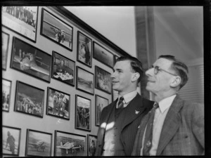 Fred North and Mervyn North, Auckland, looking at framed photographs of aeroplanes and pilots