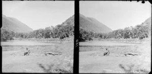 William Williams sitting next to a lake, [Fiordland National Park, Southland District?]