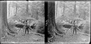 William Williams wearing a backpack and holding a walking stick, in a forest [Milford Track, Fiordland National Park, Southland District?]