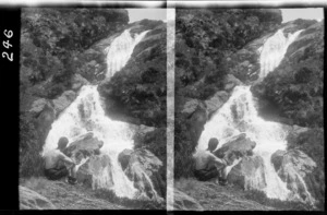 Unidentified man sitting next to a mountain cascade, [Milford track, Fiordland National Park, Southland District?]