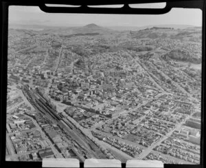 View showing Dunedin City Centre with Railway Station, Octagon with Saint Paul's Anglican Cathedral, residential and commercial buildings, Prospect Park and The Oval, Corstorphine and farmland beyond