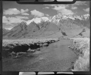 Lake Ohau, Central Otago, view of upper Huxley Valley with tussock covered valley and stream, snow covered mountains beyond