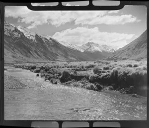 Lake Ohau, Central Otago, view of upper Huxley Valley with stream through tussock covered valley, scree slopes and bush with snow covered mountains beyond