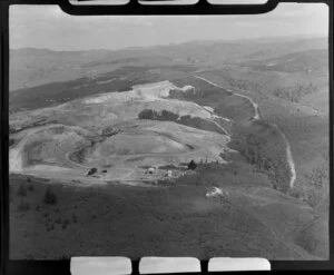 Pukemiro, Waikato District, showing open cast coal mine on hill top with buildings foreground, surrounded by bush and scrub, settlement beyond