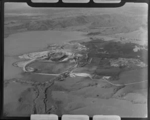 Close-up view of Huntly open cast coal mine beside lake, Waikato District, showing open pit with heavy machinery, buildings with farmland beyond