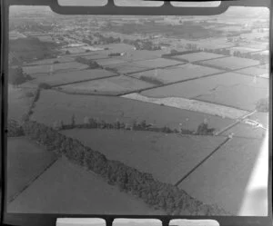 Leamington, Waikato District, view of farmland showing fields with hedgerows and power line pylons, mown field with barn, town of Leamington beyond