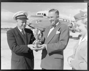 Unidentified people with a Oscar Statuette, Pan American World Airways aircraft, Whenuapai Airport, Auckland