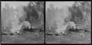 Campsite, featuring billy boiling over fire with Edgar, Owen, and William Williams sitting on a log in front of tent, Catlins area, Clutha District, Otago Region
