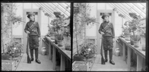 Edgar Richard Williams dressed up in military uniform [South African War?] in conservatory Williams' Royal Terrace house, Kew, Dunedin, Otago Region, including pistol, rifle and ammunition belt