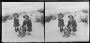 Little girl with a rifle and an unidentified man, holding two dead rabbits, Taieri Beach, South Otago