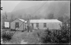 Unidentified couple outside a corrugated iron house, [Quinton Hut, Milford Track?]