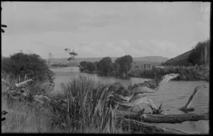 River with driftwood and flax beside it, and fencing and cleared land on the other side, unknown location
