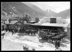 Arthur's Pass, Selwyn District, Canterbury, showing the area around the railway station on the Midland line, including a crowd and horse-drawn carriages in front of tea and refreshment rooms with mountains in background