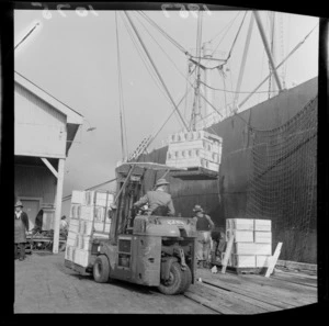 Boxes of apples [and pears?] are loaded onto a cargo ship at Port Nelson, during Apple and Pear Board celebrations for one million boxes of fruit produced