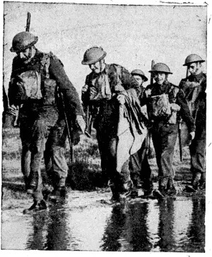 BRITAIN'S INFANTRY ON THE MARCH These stalwart young men of Britain's new infantry plough through the mud and slush while training with the cheerful disregard for conditions of Old Soldiers. (Ellesmere Guardian, 14 May 1940)
