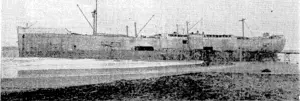 The Port Bowen today is a very different sight, with funnel and top hamper gone. Steel and machinery recovered are brought ashore by a narrow-gauge railway along the 600 ft jetty to the shore. Notices on the side of the hull proclaim the Port Bowen a " prohibited area." (Evening Post, 21 September 1940)